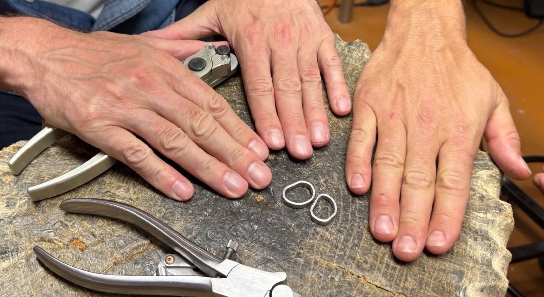 Hände neben Ringen während sie Verlobungsringe selber schmieden